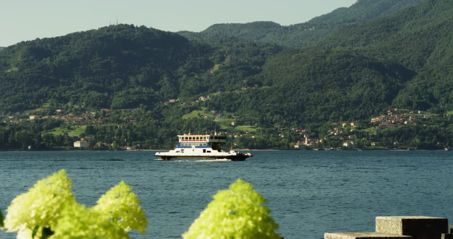 A ferry moves over the calm surface of a lake near a small town in the mountains