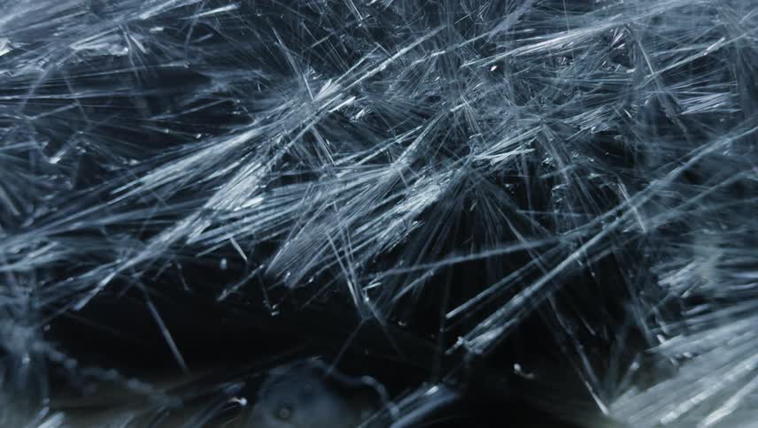 Time lapse of long thin ice crystals forming against a black background