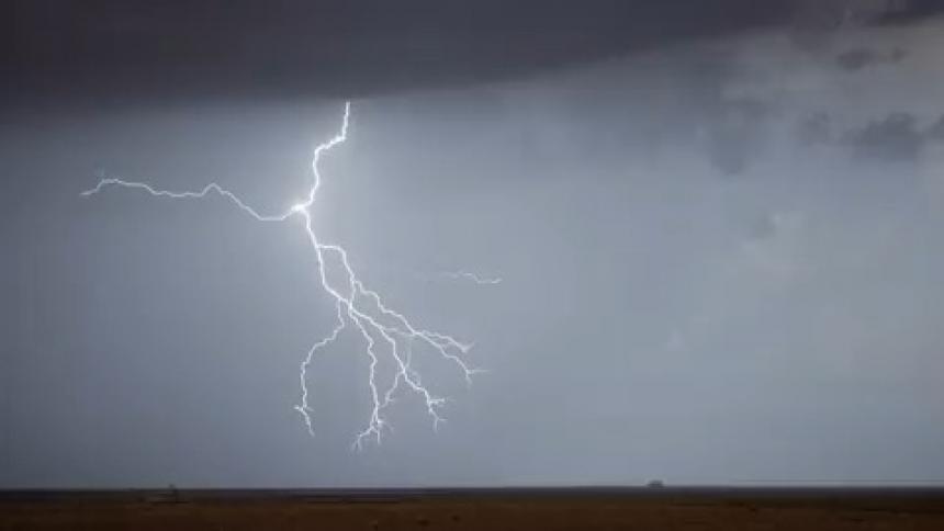 Lightning flashing across a sky over a grassland