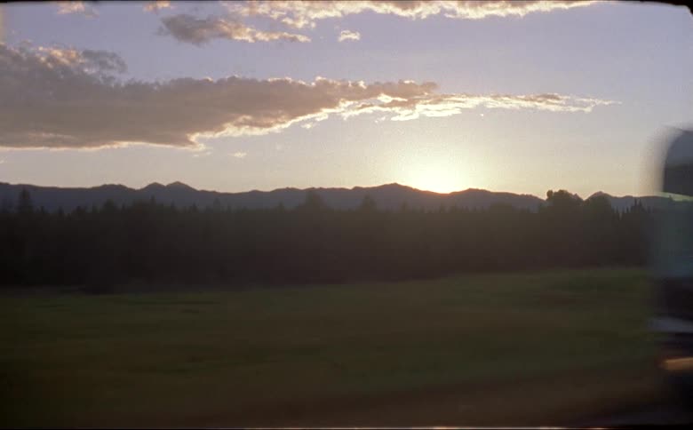 Vehicle drives on highway in the mountains at sunset shot on 16mm film