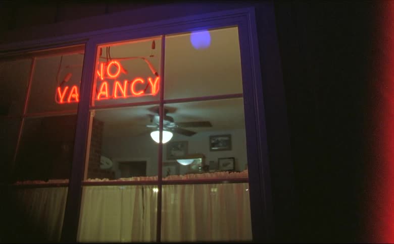 A motel with an illuminated no vacancy sign at night shot on 16mm film