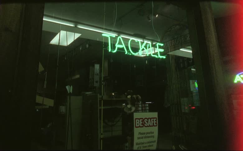 A cars taillights are reflected in the glass store front of closed tackle shop at night shot on 16mm film