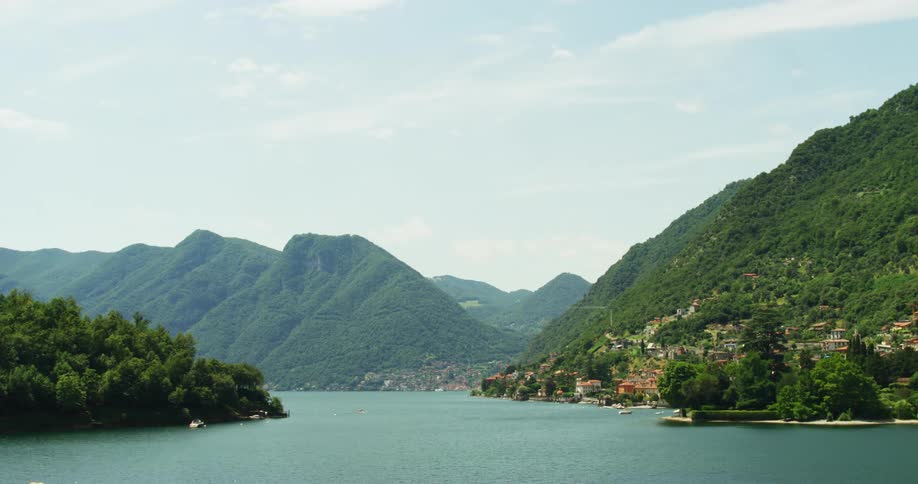 Birds flying over calm water of a coastal town at the base of green mountains and hills