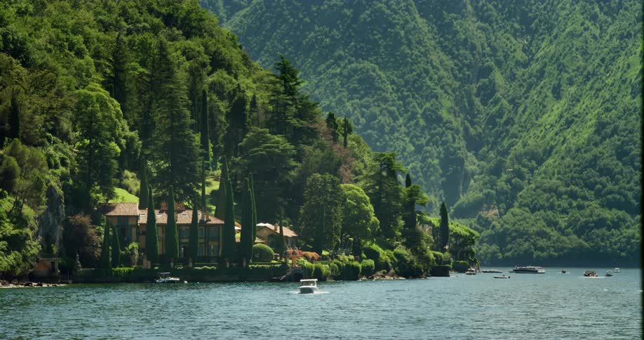 A boat floating in front of a lakeside home in summer