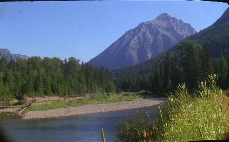 A stream flowing from a mountain with reeds blowing in the breeze shot on 16mm film