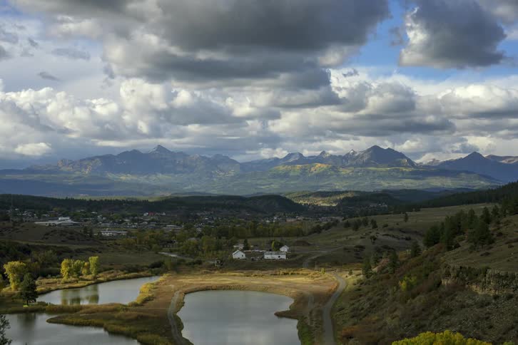 Aerial view of town next to lake under floating clouds