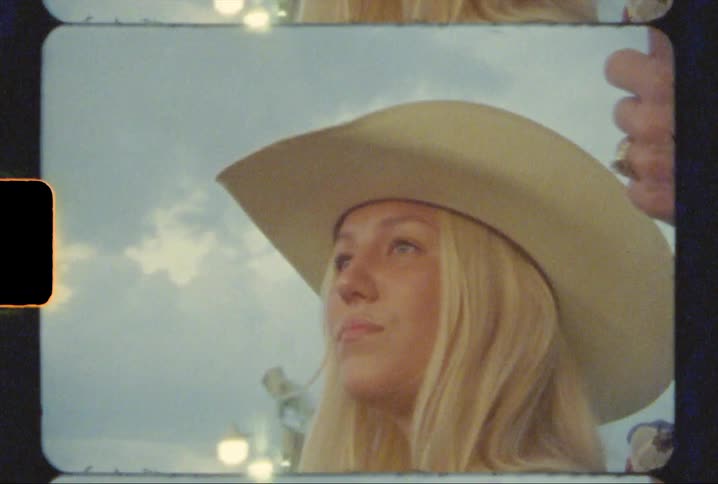 A cowgirl in the stands at a rodeo shot on 8mm film