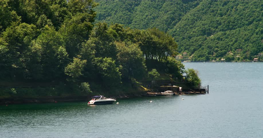 People fishing from a boat anchored near a wooden pier across from a small coastal town