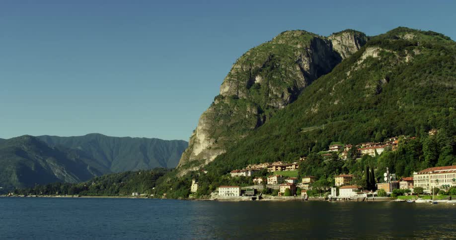 Calm surface of a lake in the mountains next to the waterfront houses of a small coastal town