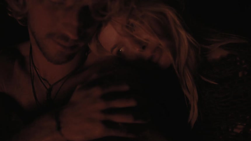 Man and woman sitting and embracing near a fire at night