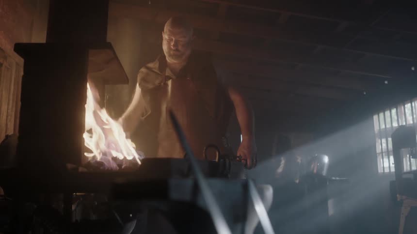 A blacksmith is arranging his tools and tending to his fire