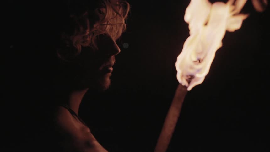 A man searches around a dark area with a torch