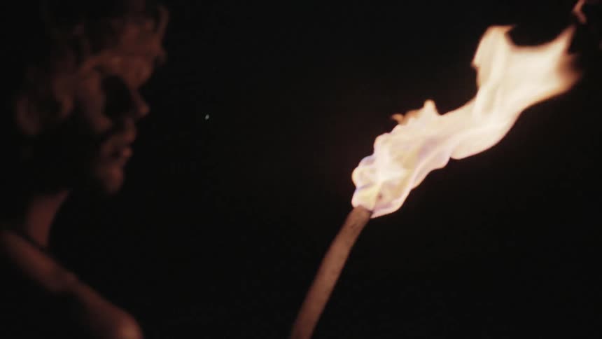 A man is looking around a dark area holding a torch