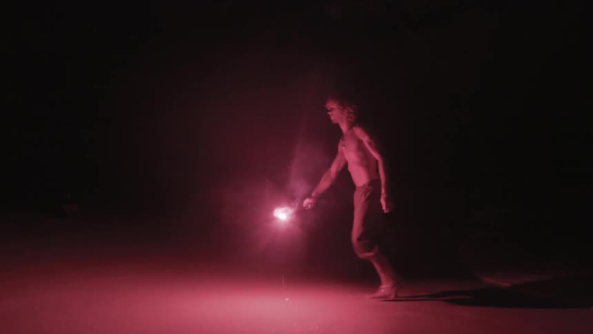 A man is walking in the dark with a flare