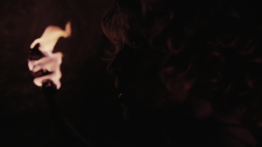A man holding a torch looks around a dark area