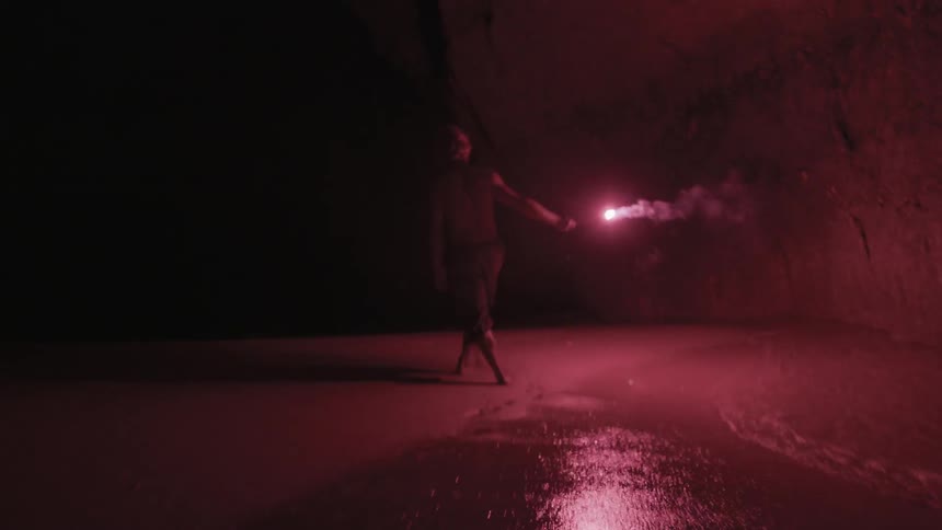 A man walks around in the dark with a flare