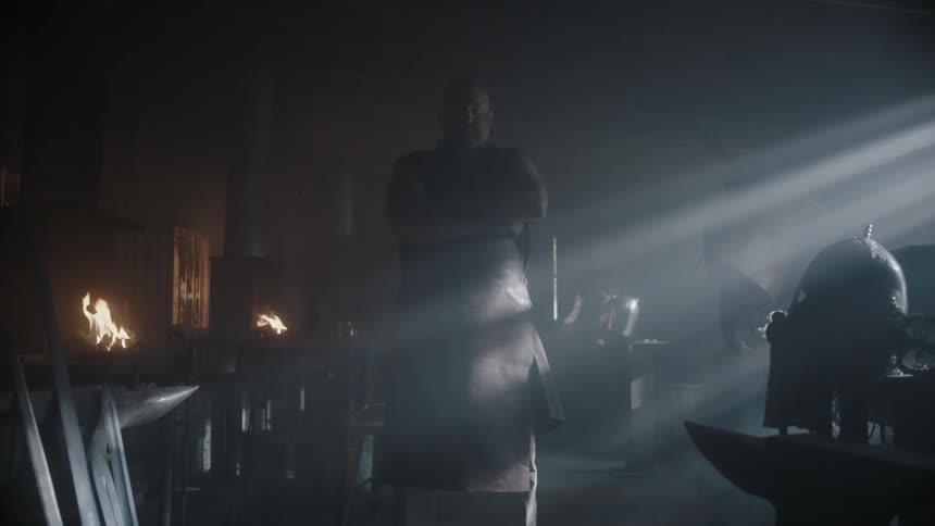A large man stands in a building near small fires