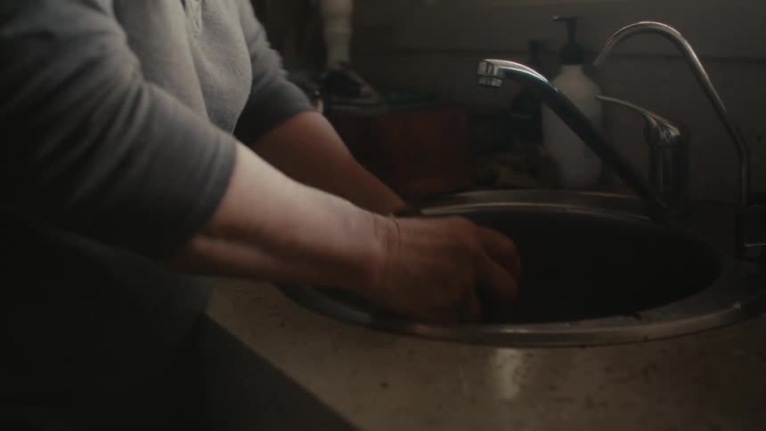 A woman washing potatoes in a home kitchen sink