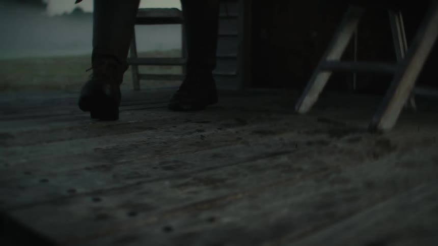 Silhouette of the legs of a person walking over a wooden board floor