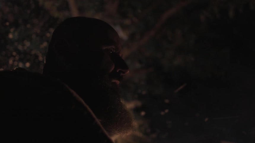 A man looks around at night as sparks from a fire fly