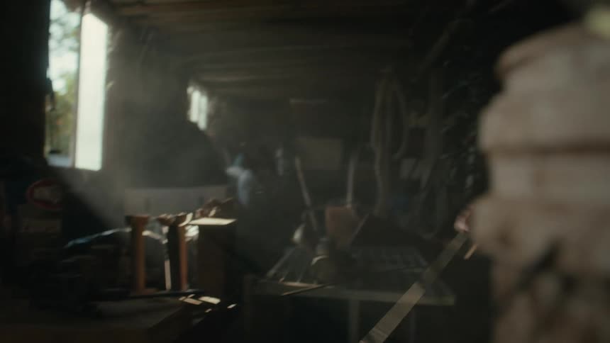 Farmer uses tools to bend rebar on a dusty dimly lit shed in the morning