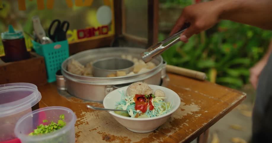 A man serves himself food while another man points for him to take more