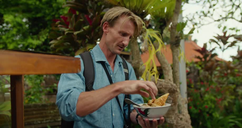 Tourist standing on a lush green garden has a taste of the local cuisine on vacation