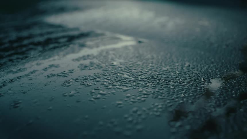 A smooth reflective surface covered in water droplets