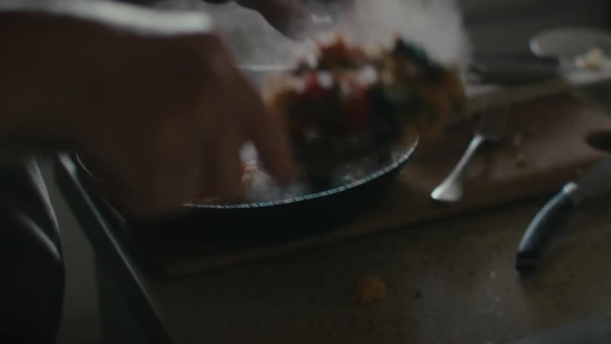 A person uses a spatula to remove food from a skillet and place it on a plate