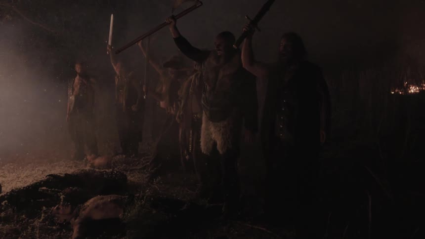 Men raising their swords in the air as they stand near dead bodies and a fire