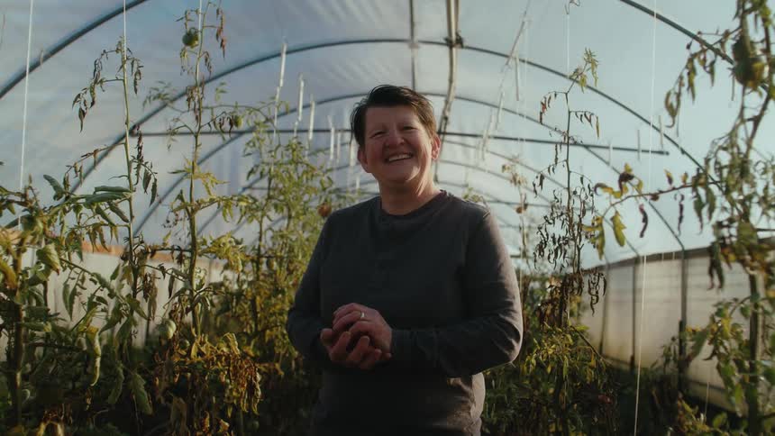 Happy farmer smiles while holding fruits harvested from the greenhouse