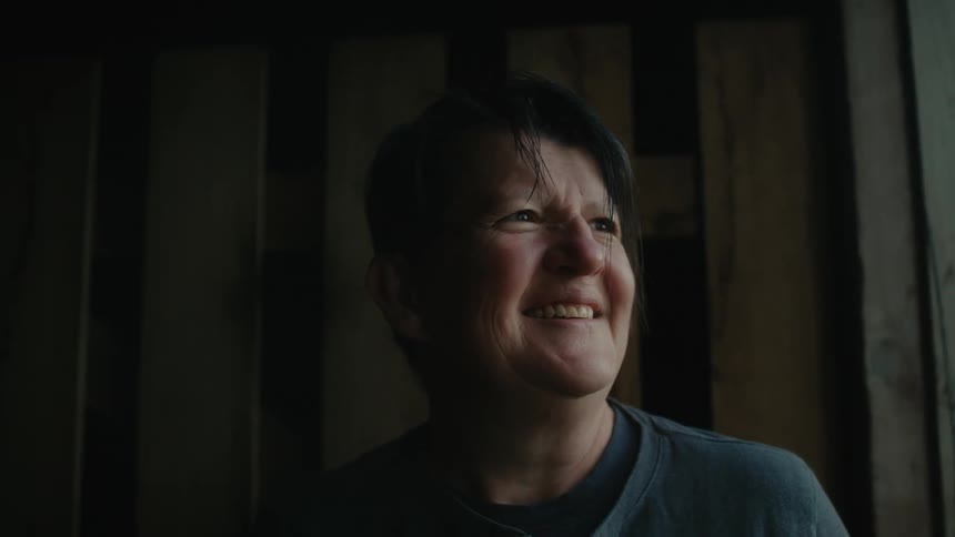 A woman laughs while sitting near a window
