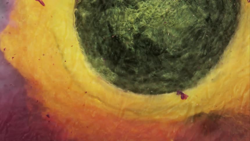 Yellow and orange are blending together and a dark circle bursts out and pushes away the colors then shrinks and yellow fills the area