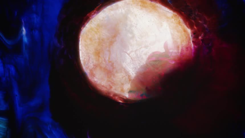 Blob of bright red and white ink expands and contracts like an exploding star over a dark background