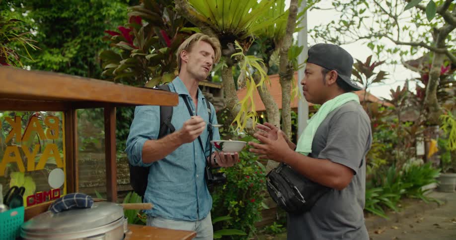 Tourist enjoys a meal from a street vendor on the side of the street of a small town