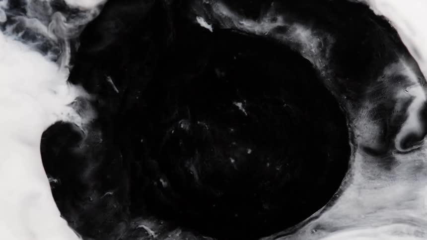 A white substance bursts and spreads as it blends into the darkness