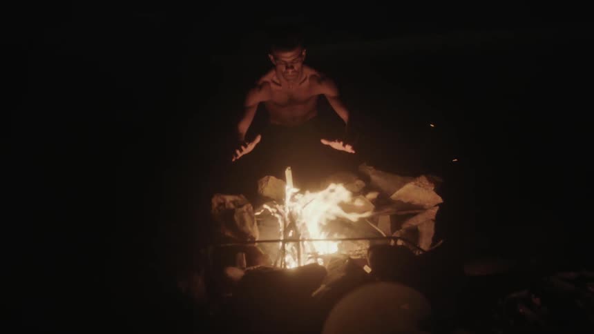 A man warms his hands on a fire