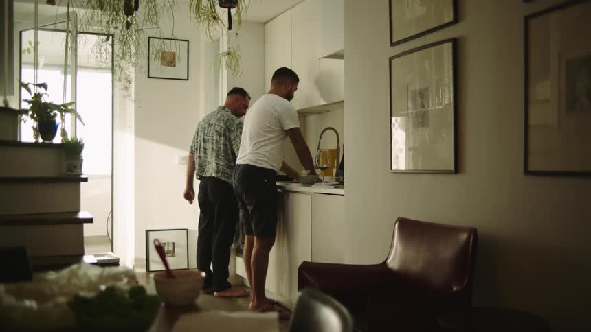 A man brings dishes to the kitchen for his partner to wash