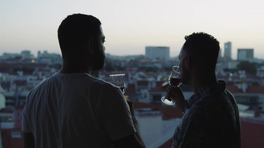 Two guys drinking wine and kissing outdoors
