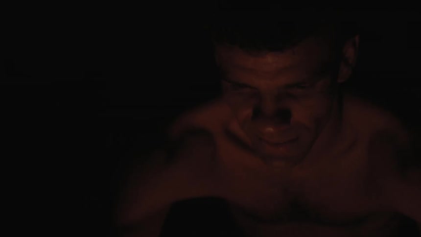A sitting man looks at a fire at night