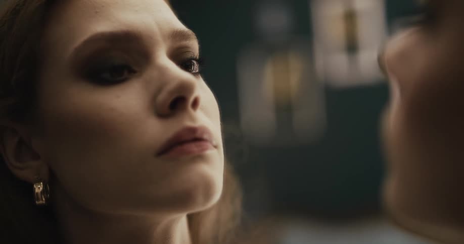 Close up of a young beautiful woman intensely looking at herself in a mirror