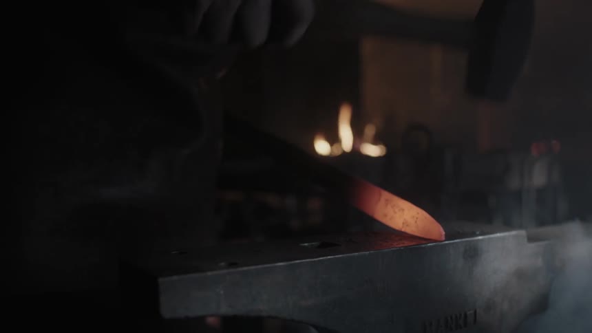 A person is hammering hot metal on an anvil