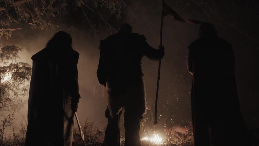 Three men stand in front of a fire