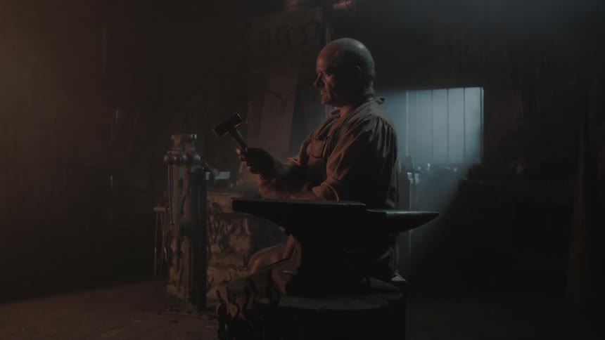 A blacksmith studying a hammer