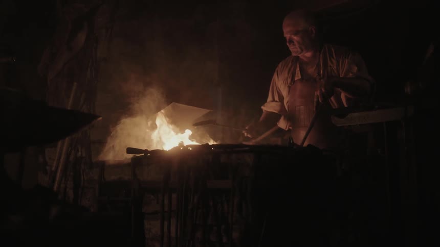 A man tends to a fire in the dark