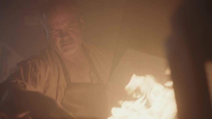 A man works in front of a blazing fire