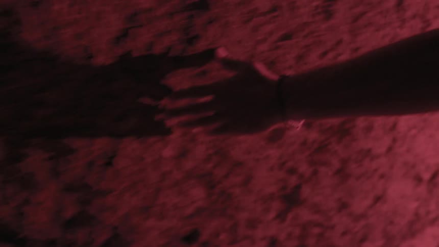 A person is tracing their hands against a stone wall