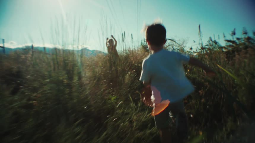 Two children are playing and running through a field of weeds