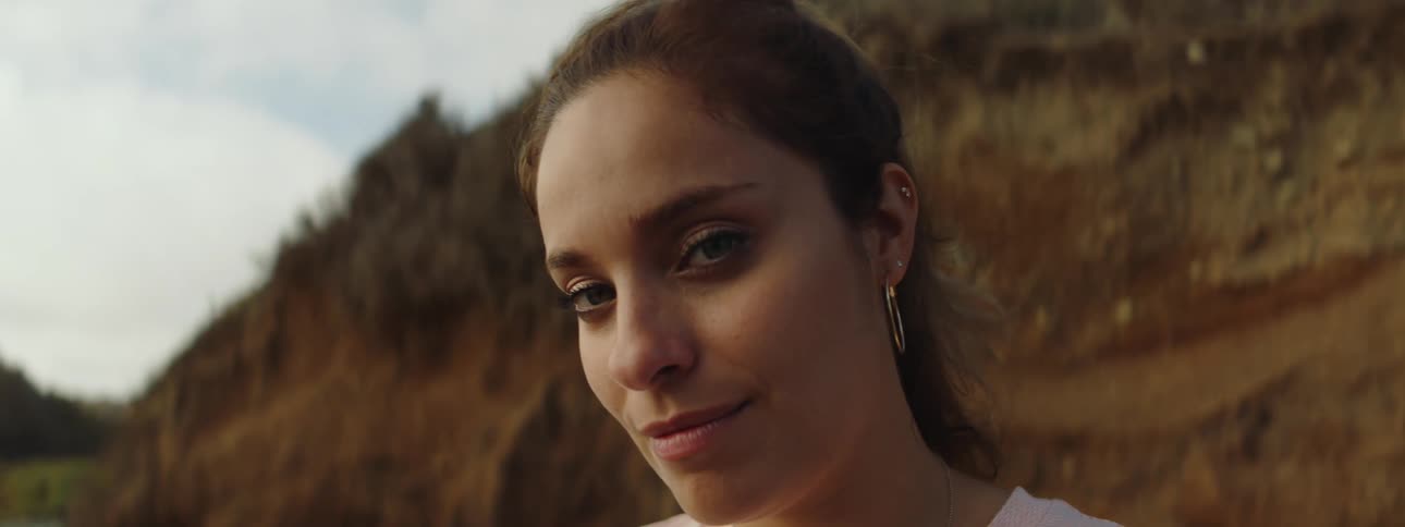 Young woman standing near a cliff turns to look at the camera