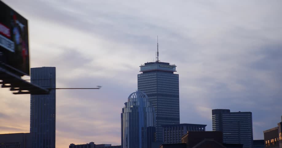 Series of billboards line road with downtown skyscrapers in the background